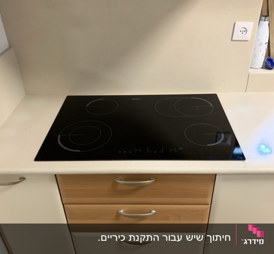 משטח שיש לבן עם כיריים שחורות במטבח מודרני